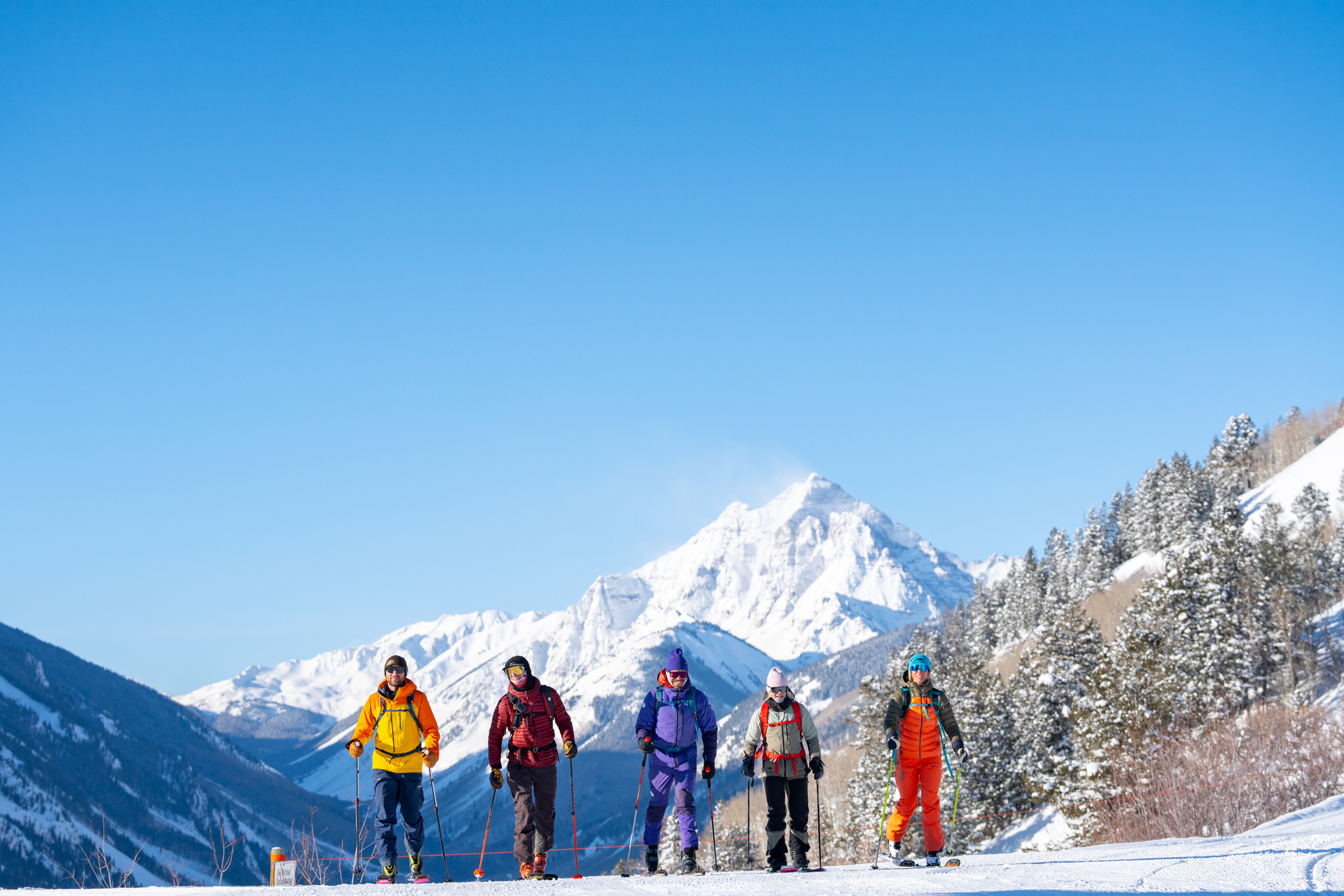 Friends reach the top of a ridge while uphill skiing.