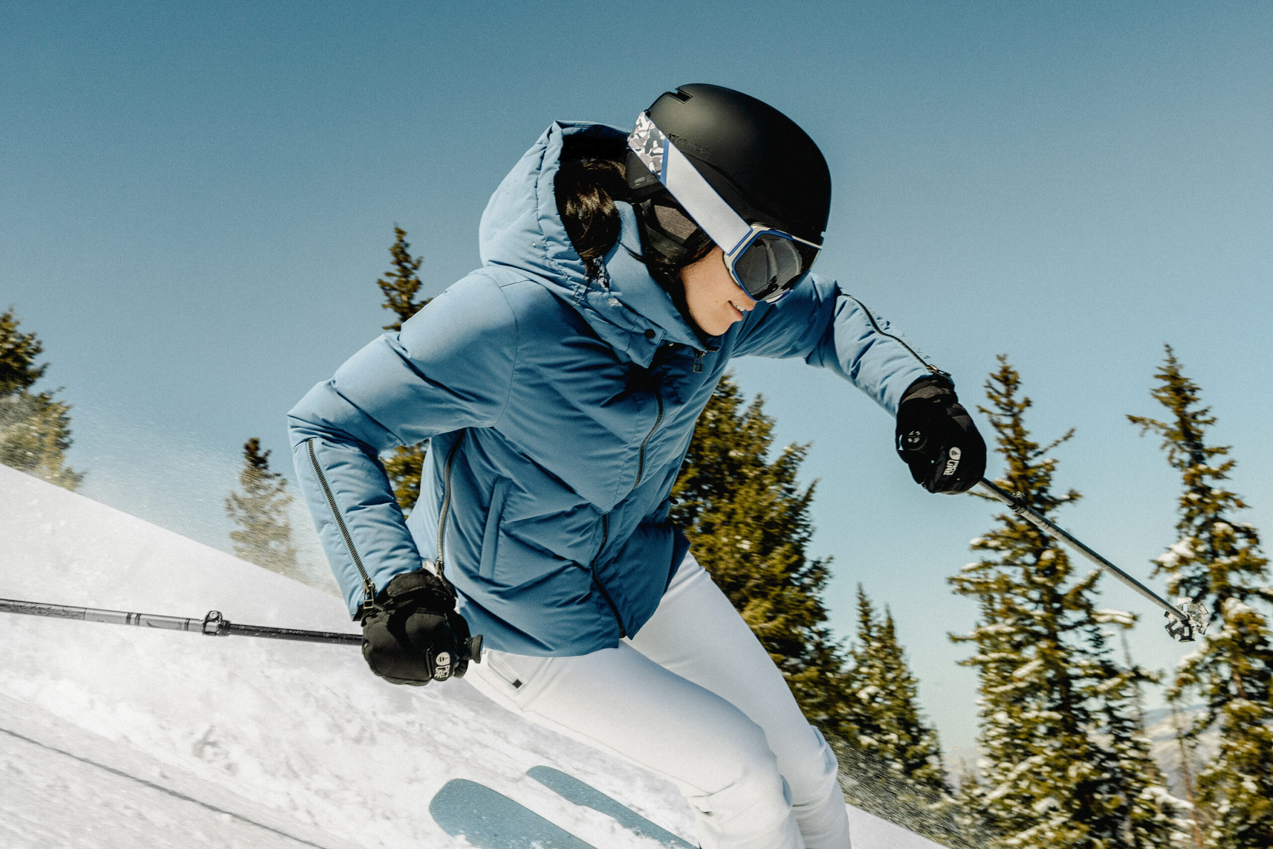 Women skiing in blue jacket and white pants from Aspen Collection