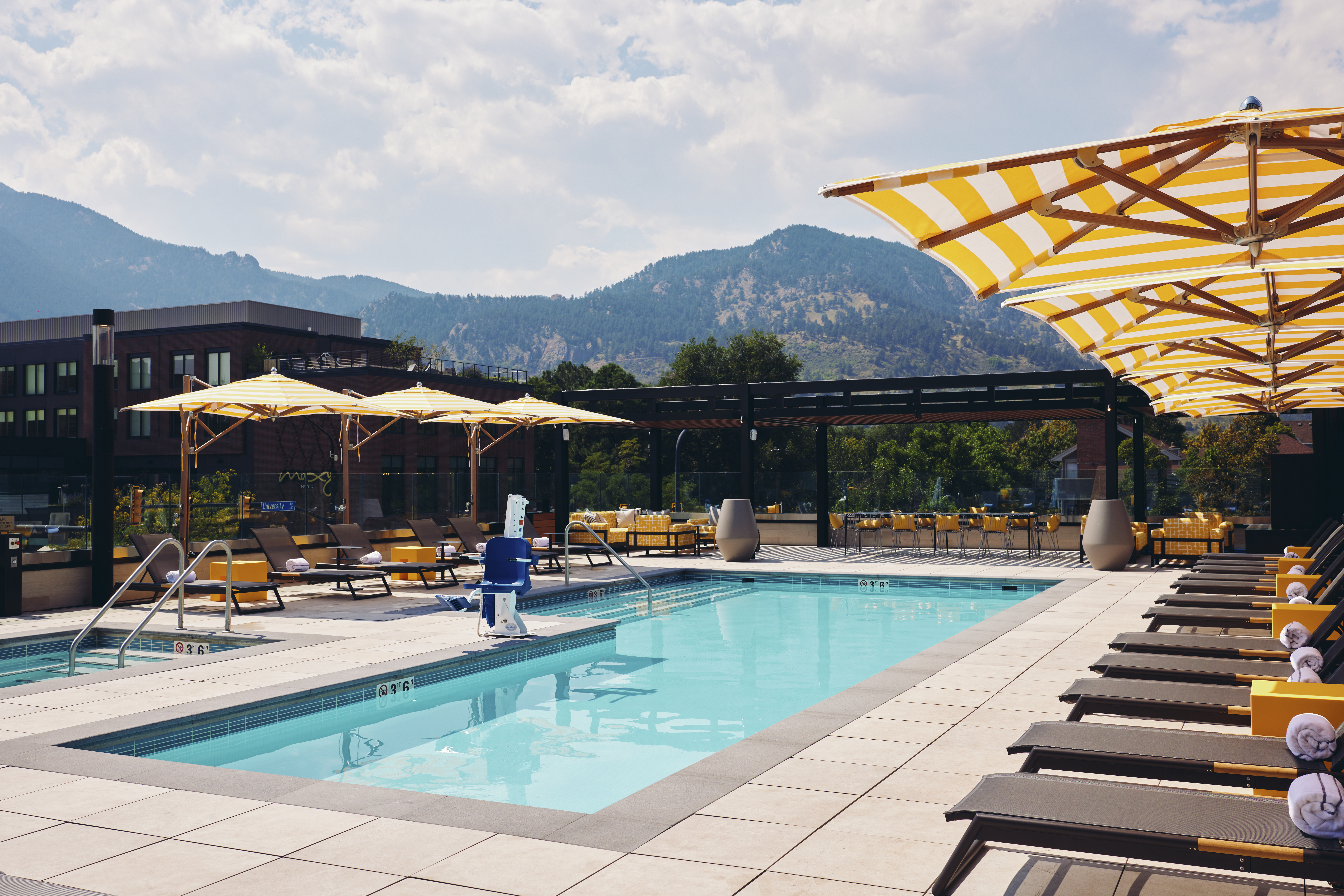 Limelight Boulder pool, blue water with yellow umbrellas, Boulder Flatirons in the background