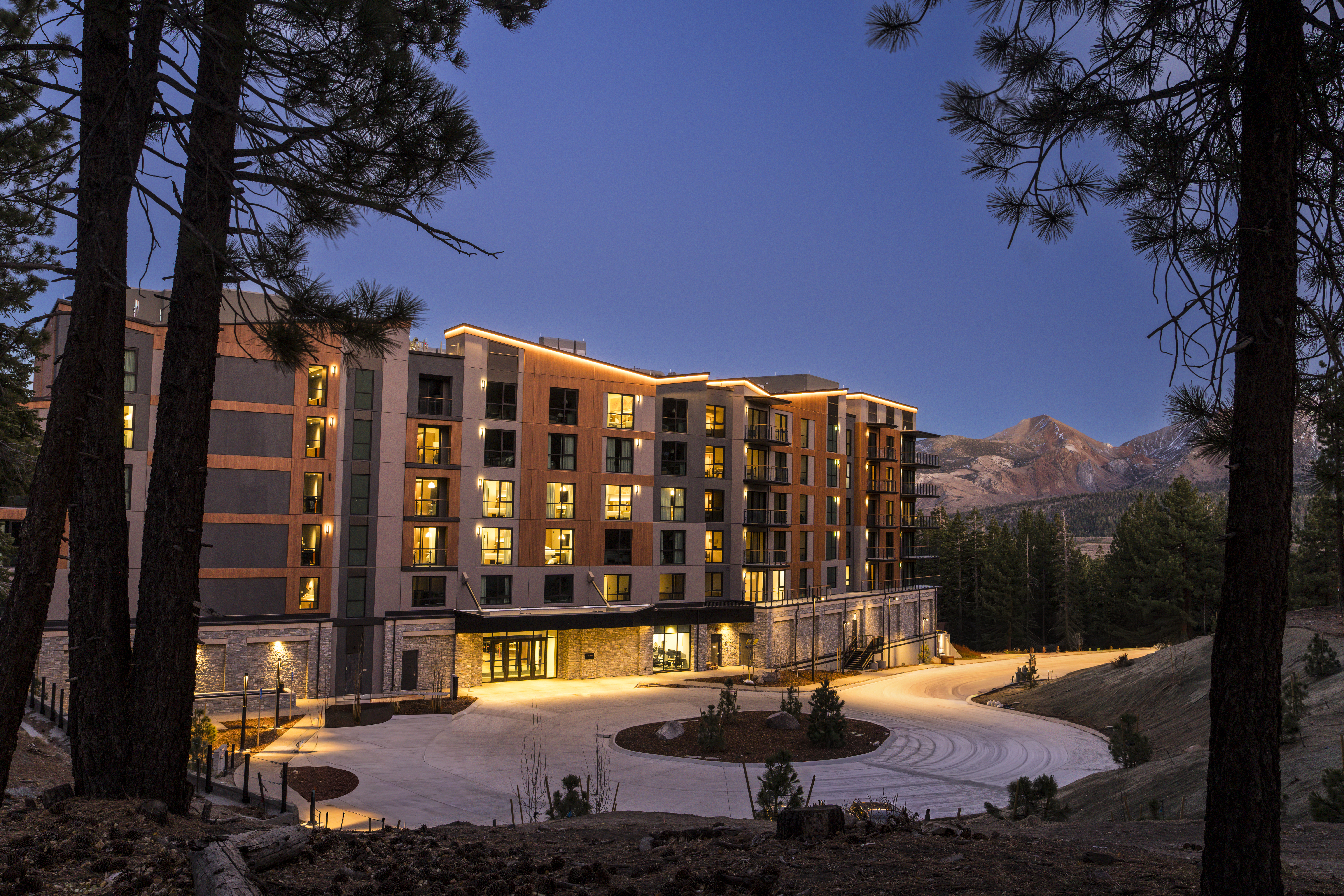 Exterior view of limelight Mammoth, white courtyard with stark, stunning mountains highlighted in background