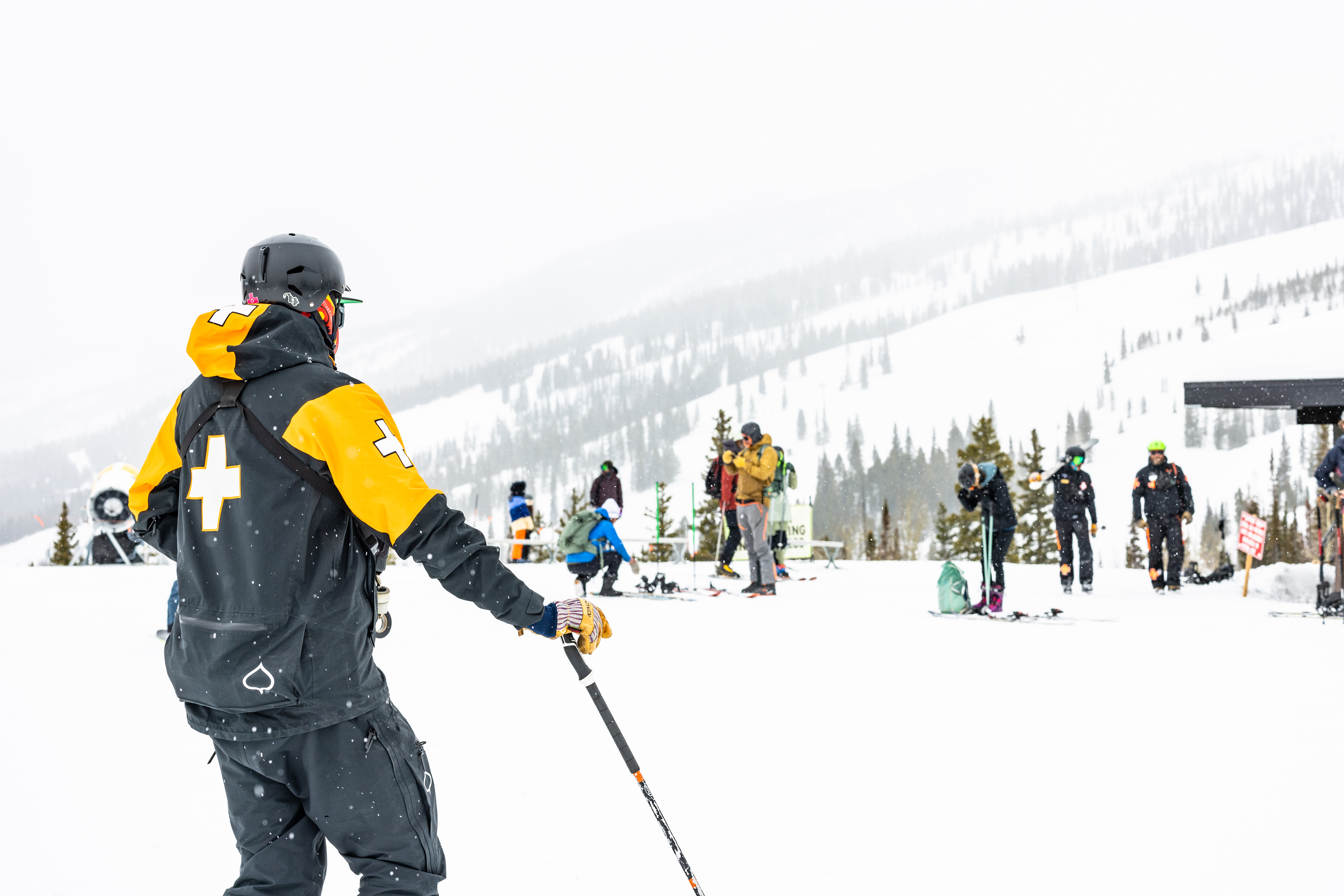 Ski Patroller from the back, as they look over a crowd of people at aspen snowmass